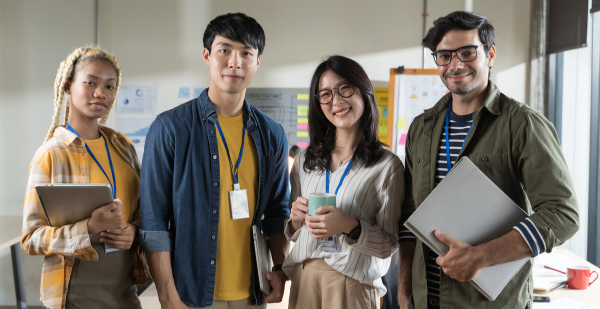 Three people standing next to each other holding a laptop.